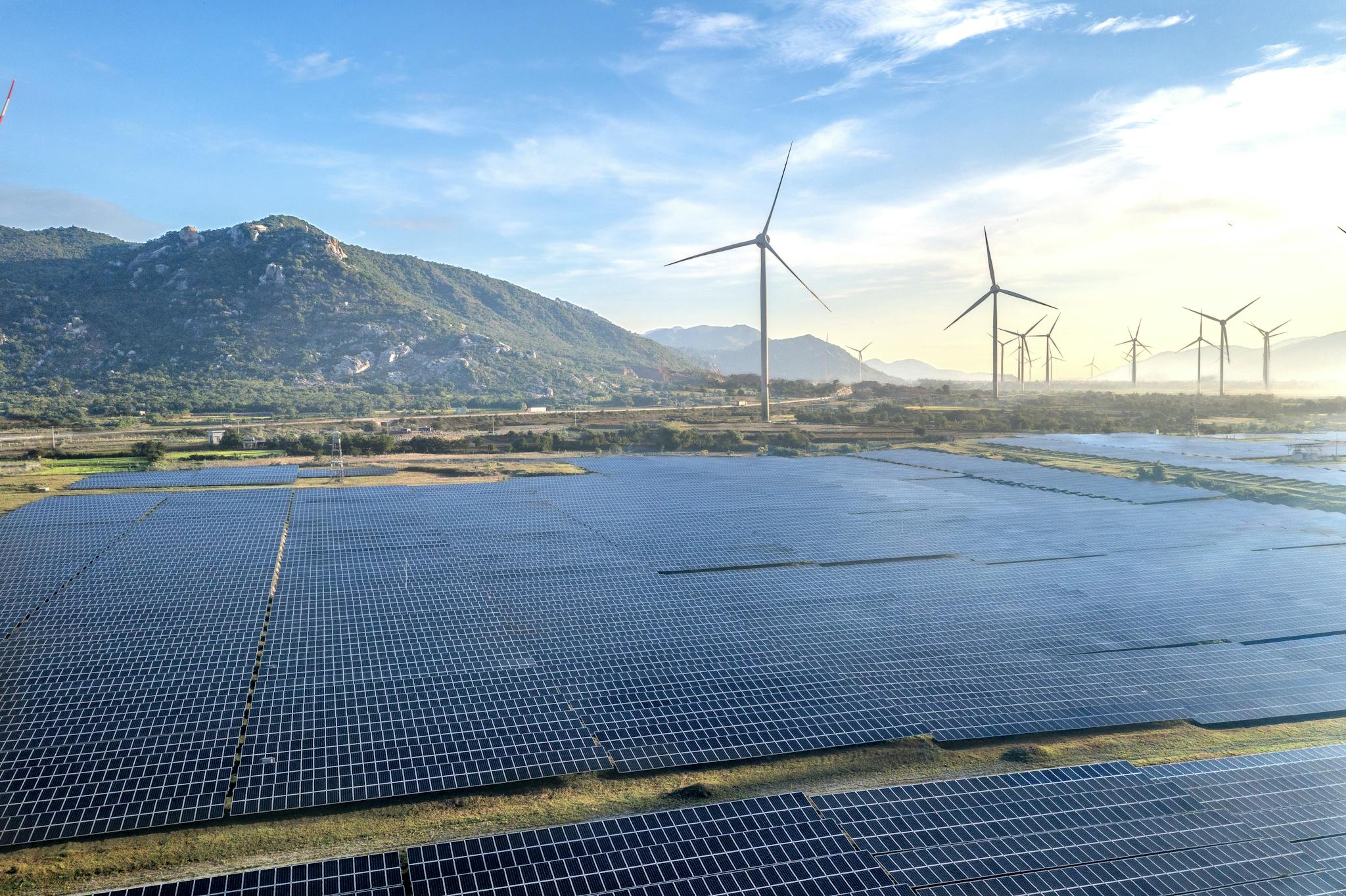 Aerial view of a solar and wind energy farm set against Vietnam's scenic landscape.